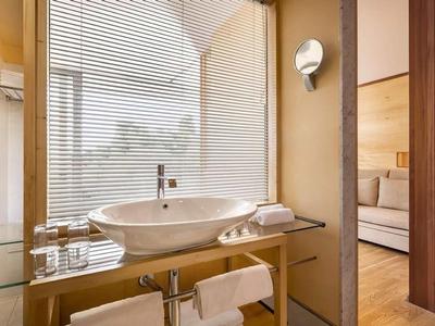 Bagno moderno con lavandino rotondo, pareti in vetro e vista sul soggiorno.