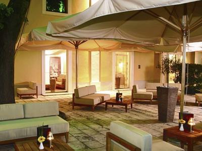 Accogliente terrazza illuminata con poltrone e tavoli sotto grandi ombrelloni.