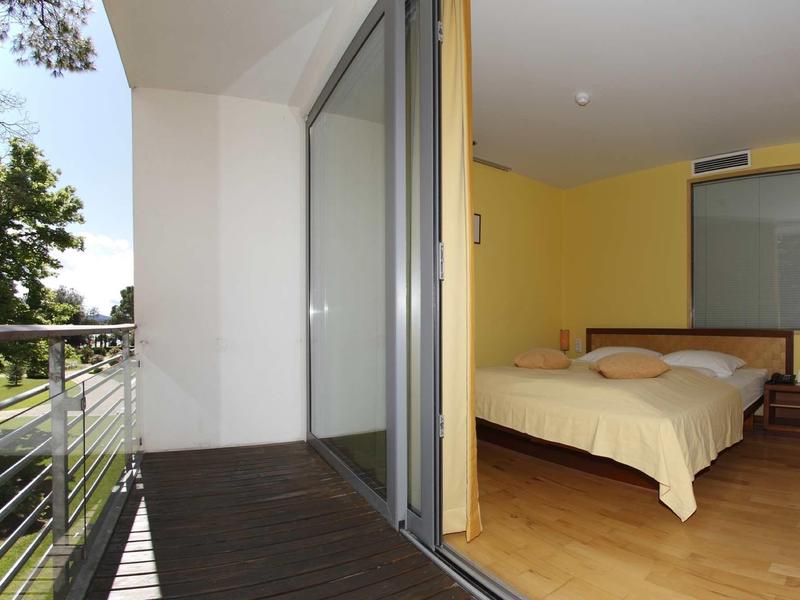 Vista da un balcone su una camera da letto con letto grande e comodino.