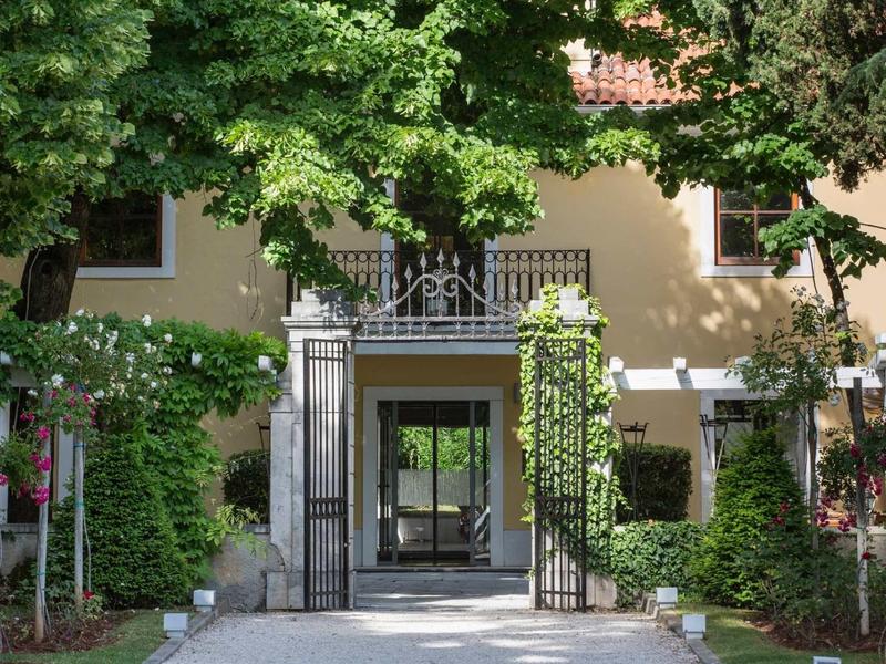 Ingresso dell'hotel con fogliame verde e passaggio coperto.