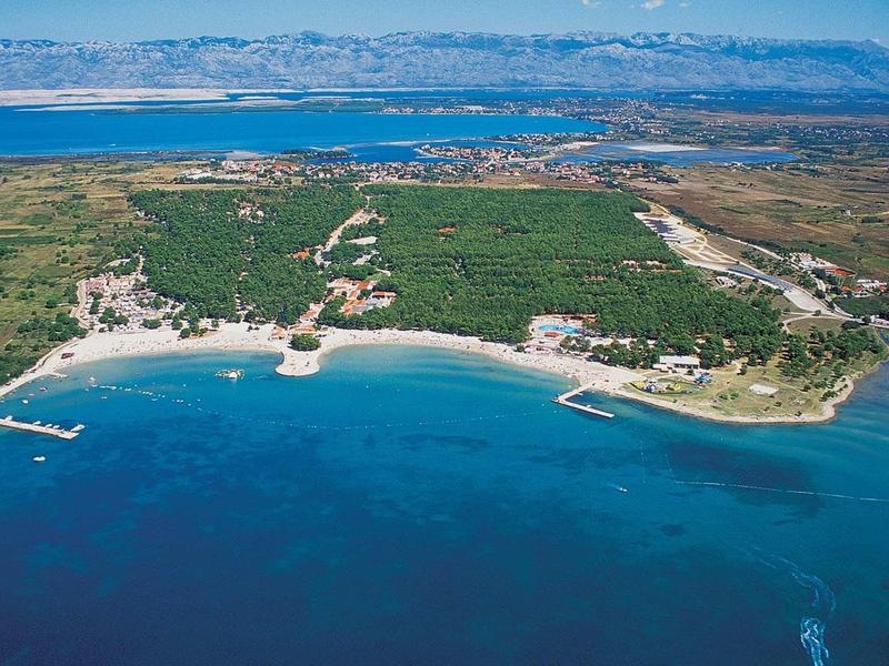 Aerial view of a coast with blue sea, sandy beaches, and green areas.