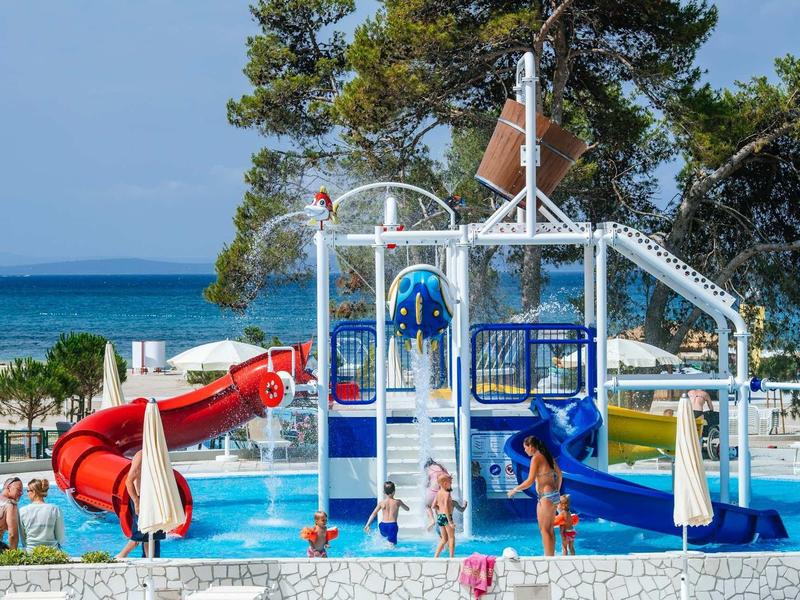 Colorful water playground with slides and splash pool by the beach and sea