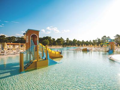 Piscina ricreativa con scivoli d'acqua e giochi sotto un cielo limpido in un resort.