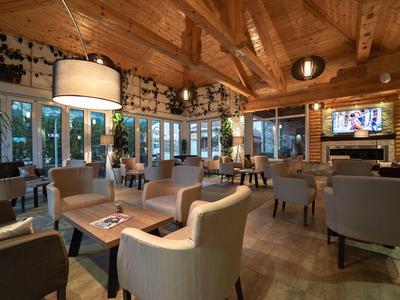 Espace lounge d'hôtel confortable avec fauteuils, murs en bois et grandes fenêtres.