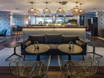 Bar d'hôtel moderne avec tables rondes et tabourets élégants dans une ambiance conviviale.