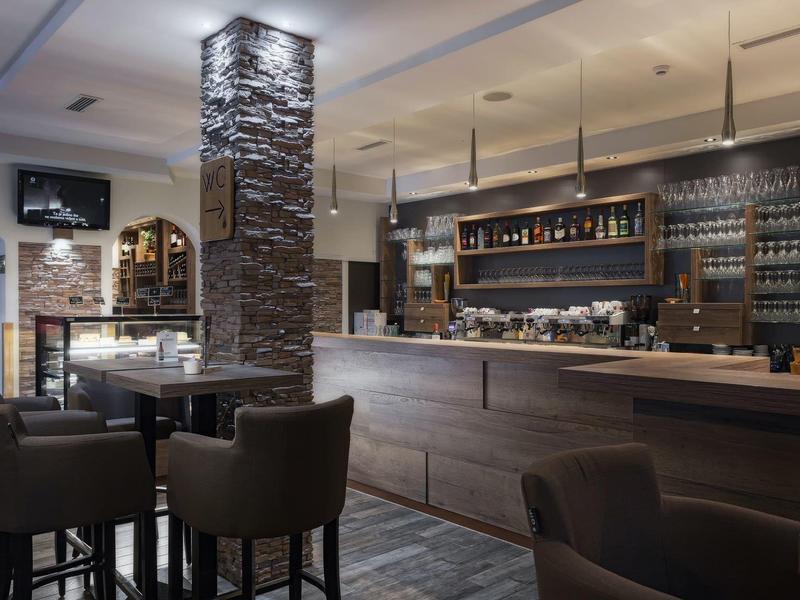 Nowoczesny bar hotelowy z drewnianymi meblami, kamienną kolumną i wygodnymi miejscami do siedzenia.