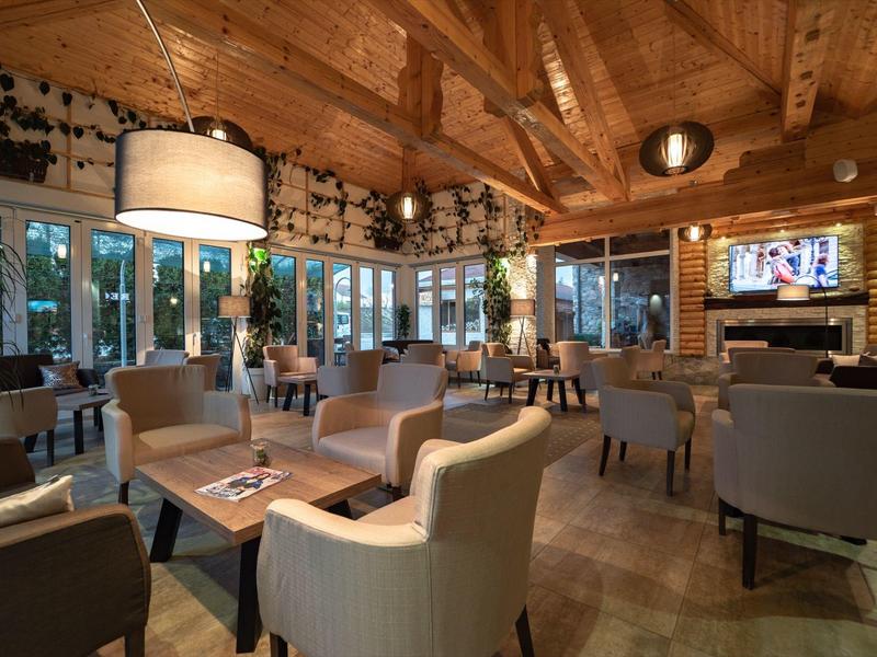 Przytulny salon hotelowy z rustykalnym, drewnianym wnętrzem i wygodnymi fotelami.