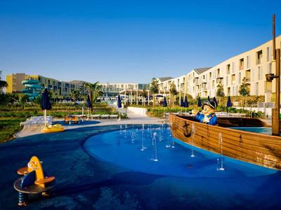 Piscine d'hôtel moderne avec aire de jeux et zone aquatique en forme de bateau par temps ensoleillé
