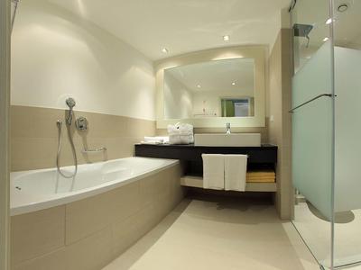 Salle de bains moderne avec baignoire, lavabo et cabine de douche en verre aux tons neutres.