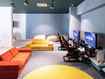 Moderní místnost se žlutou a červenou pohovkou a herním zařízením napravo.