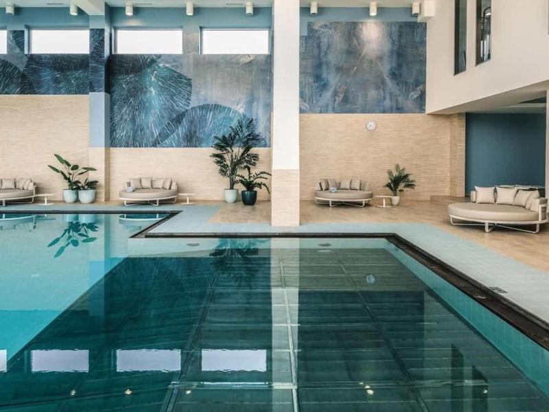 Moderní vnitřní bazén s průzračnými modrými dlaždicemi a pohodlnými posezeními