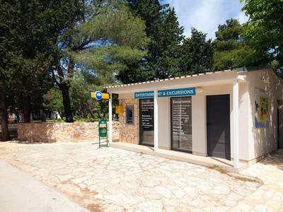 Small white building with closed doors in a wooded recreational area.