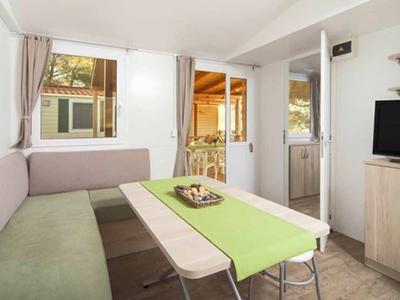 Eethoek met hoeksalon, tafel met groene loper en stoelen in een lichte kamer.