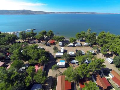 Aerial view of a campsite with motorhomes and tents beside a large lake.