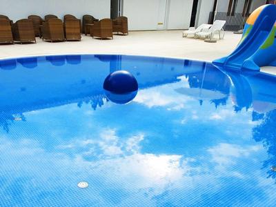 Swimming pool with blue slide and sun loungers on a sunny day