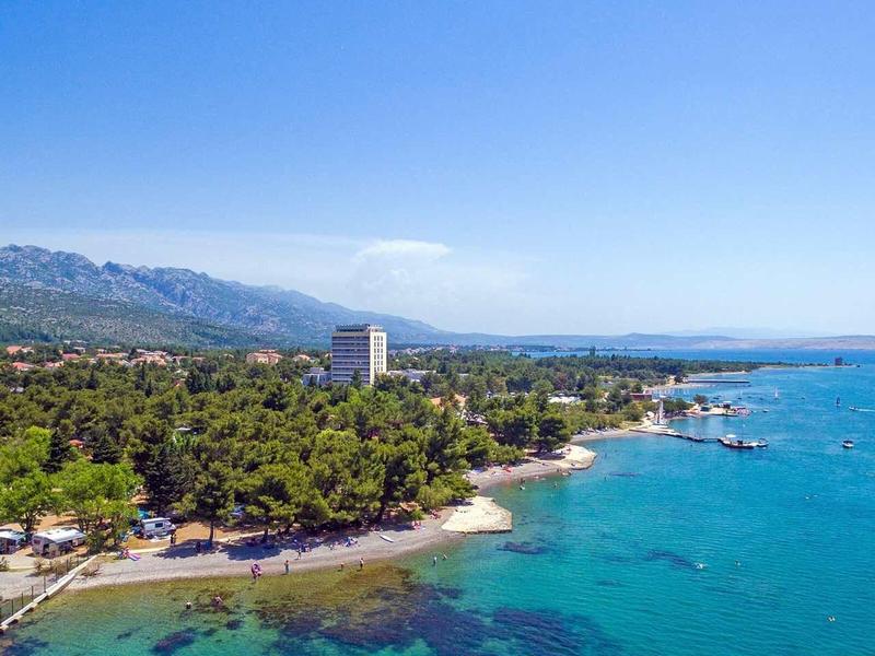 Coastline with turquoise water, beach, and forested area under clear sky