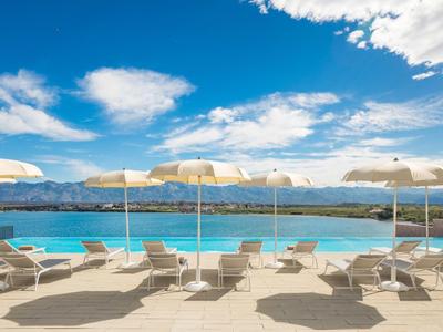Area piscina con lettini e ombrelloni con vista su montagne e lago sotto il cielo azzurro