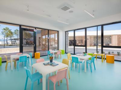 Salle lumineuse et moderne avec des chaises et des tables colorées devant de grandes fenêtres.