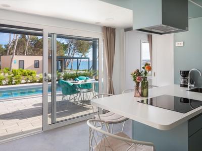 Cuisine moderne avec vue sur la terrasse, la piscine et la mer en arrière-plan.