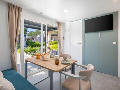 Coin repas moderne avec table, chaises et canapé donnant sur un jardin.