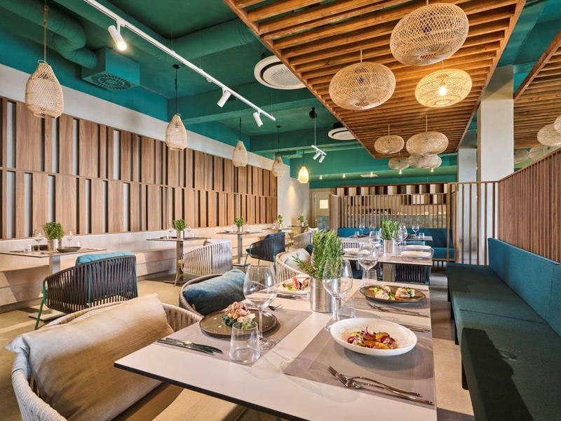 Restaurant moderne avec éléments en bois, grandes fenêtres et tables élégamment dressées.