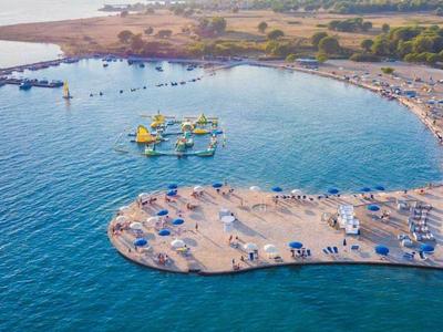 Zdjęcie z lotu ptaka piaszczystej plaży z parasolami obok czystej niebieskiej wody i lądu.