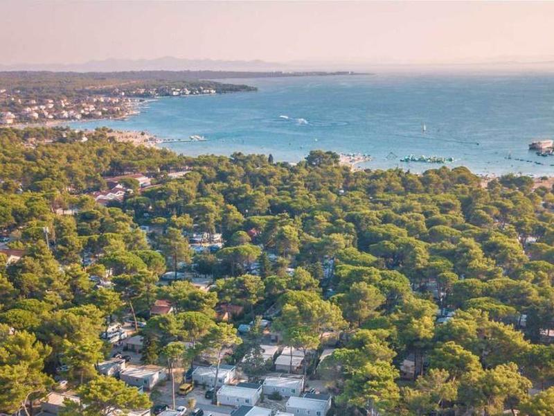 Widok z powietrza na zalesiony obszar przybrzeżny z łodzią na niebieskim morzu.