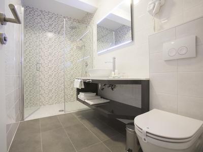 Modern bathroom with walk-in shower, wall-mounted toilet, and large mirror.