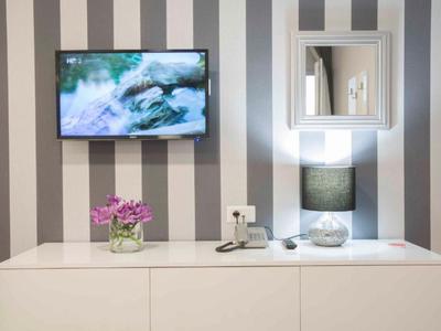 Modern hotel room cabinet with TV, mirror, lamp, and flower decoration.