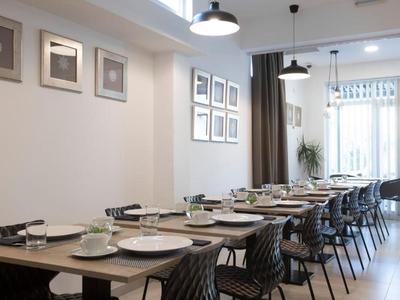 Sala da pranzo moderna con tavoli apparecchiati e sedie in uno spazio luminoso.