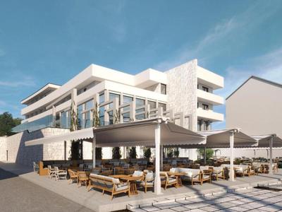 Modernes Hotel mit außenliegendem Sitzbereich und Sonnenmarkisen unter blauem Himmel.