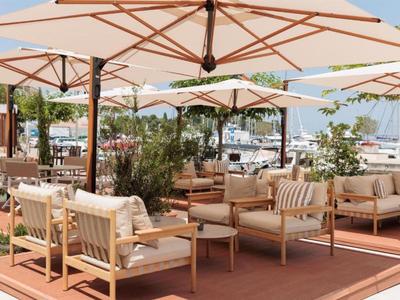 Gemütliche Außenlounge mit bequemen Sesseln und Sonnenschirmen am Wasserhafen.