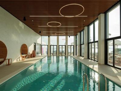 Moderner Innenpool mit Holzdecke, großen Fenstern und Tageslicht.