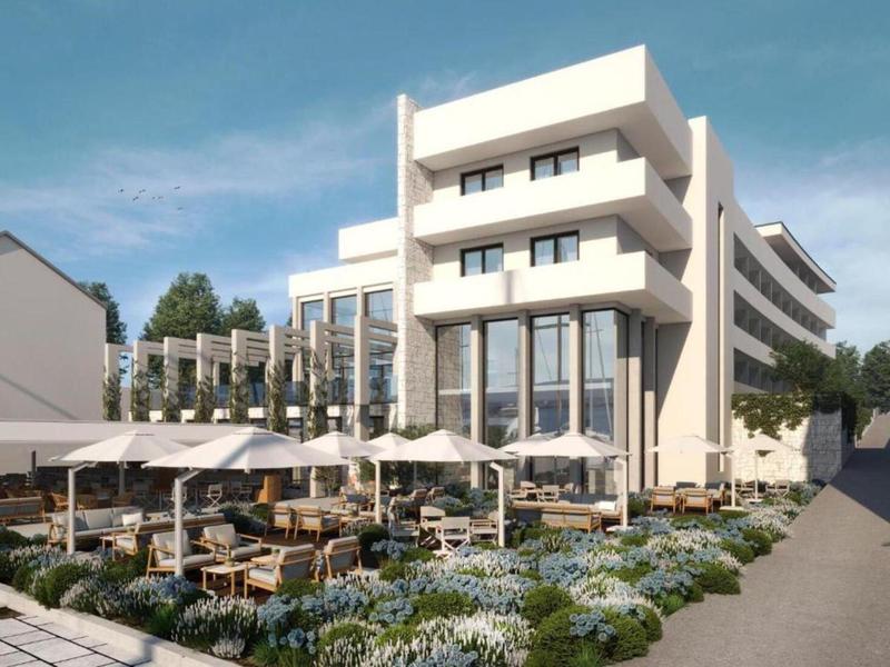 Hôtel moderne avec terrasse et parasols, entouré de fleurs et de plantes