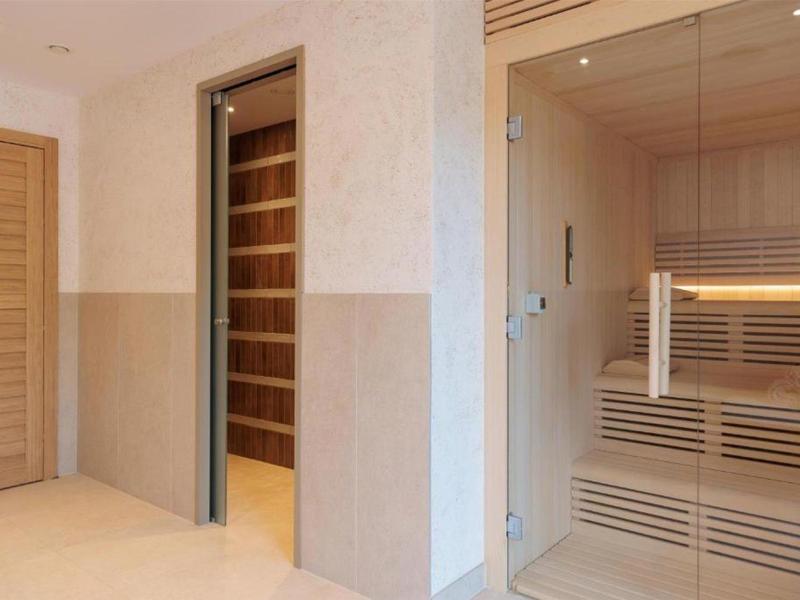 Espace sauna moderne avec façade en verre et intérieur en bois dans un coin calme de l'hôtel.