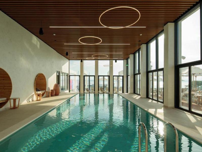 Piscine intérieure élégante avec grandes fenêtres et éléments modernes en bois au plafond