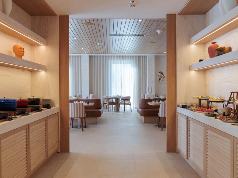 Salle à manger d'hôtel moderne avec buffet ouvert et coin repas aux tons neutres.