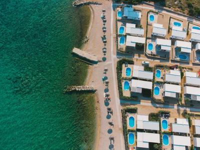 Strandhotel mit Poolanlagen direkt am türkisfarbenen Meer und einem sandigen Uferabschnitt.