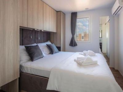 Modernes Hotelzimmer mit Doppelbett, weißen Bettwaren und Holzmöbeln in neutralen Farben.