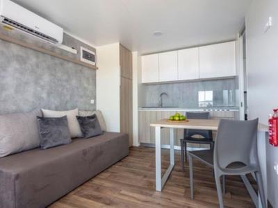Kleines, modernes Apartment mit Küchenzeile, Sofa und Esstisch in neutralen Farbtönen.