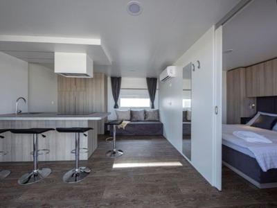Modern eingerichtetes Hotelzimmer mit Küche, Essbereich und angrenzendem Schlafzimmer.