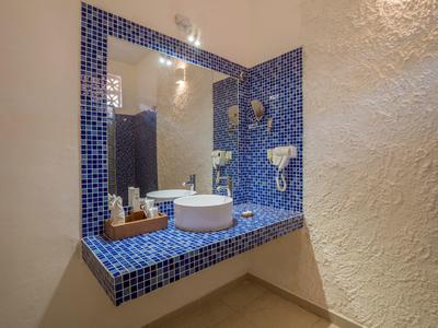 Badezimmer mit eckigem Waschbecken und blauen Mosaikfliesen an Wand und Waschbeckenablage.