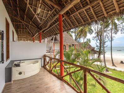 Balkon mit Rundbadewanne, Holzbalken und Blick auf Palmen und Strand am Meer.