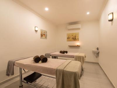 Behandlungsraum mit zwei Massageliegen, weißen Wänden, sanfter Beleuchtung und ruhiger Atmosphäre.