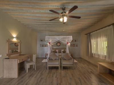 Großes Schlafzimmer mit Holzbalkendecke, Doppelbett, Schreibtisch, Ventilator und großen Fenstern.