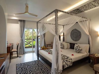 Elegantes Schlafzimmer mit Himmelbett, Zebra-Teppich und Balkon mit Blick ins Grüne.