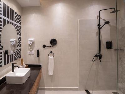 Modernes Badezimmer mit Waschbecken, rundem Spiegel und Walk-In-Dusche mit Glasabtrennung.