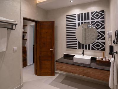 Moderner Hotelbadezimmerbereich mit Waschbecken, rundem Spiegel und offener Holztür