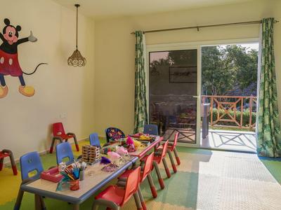 Bunter Kinderraum mit kleinem Tisch, Stühlen, Spielsachen und großer Glasschiebetür zum Garten.