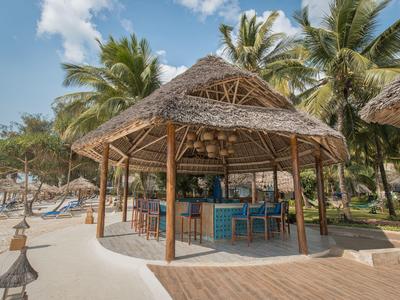 Offener Pavillon mit Strohdach und blauen Barhockern, umgeben von Sand und Palmen.